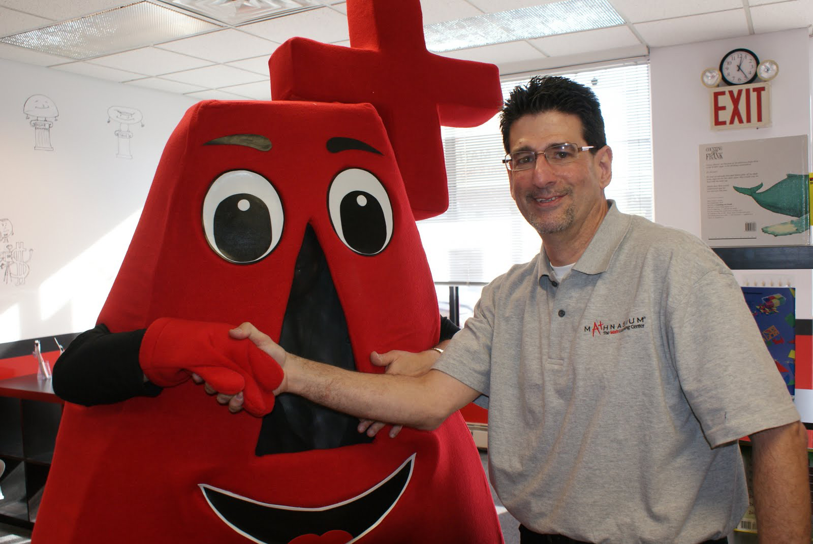 Mathnasium of New Hyde Park center director Peter Abrams greets mascot A+ at the grand opening on January 16.